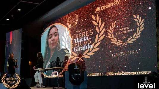Pantalla con María Giraldo como ganadora Mujer Tecnología 2022 y público en el escenario de Mujeres Épicas de Revista Level