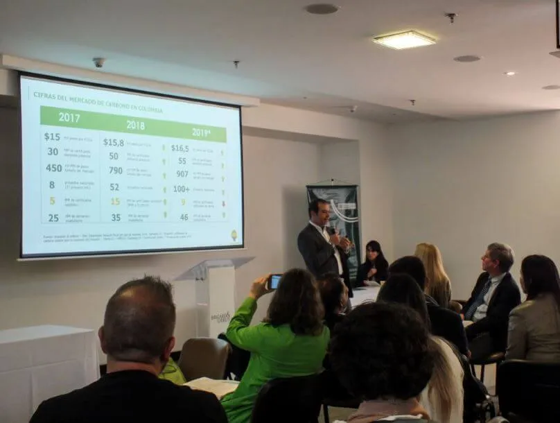 Mauricio Rodríguez, de Co2cero, presenta ante el público junto a una pantalla con una tabla, en el Foro y Rueda de Negocios Verdes