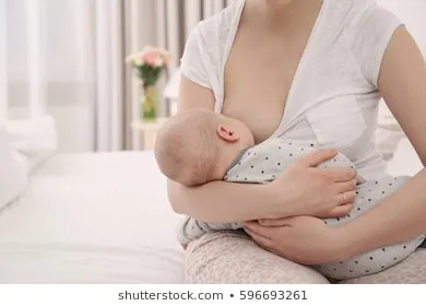 Mujer amamantando a un bebé en brazos sobre una cama