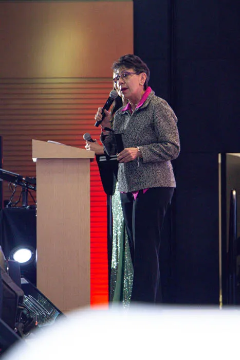 Mujer habla con un micrófono en un atril y sostiene un trofeo durante la premiación Mujeres Épicas 2022