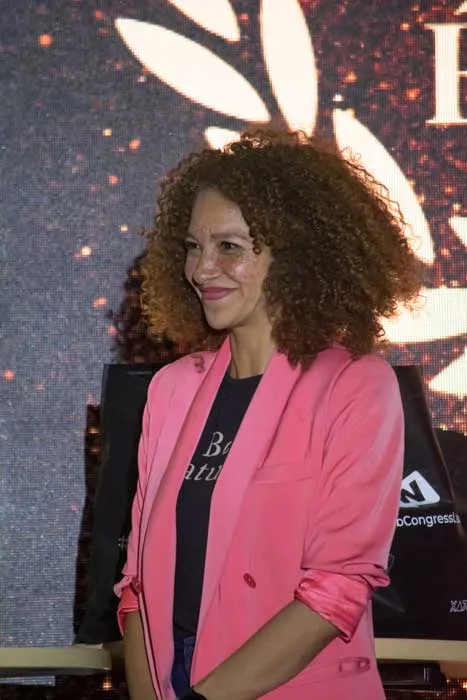 Mujer de cabello rizado y blazer rosa sonríe durante la gala de los Premios Mujeres Épicas 2023