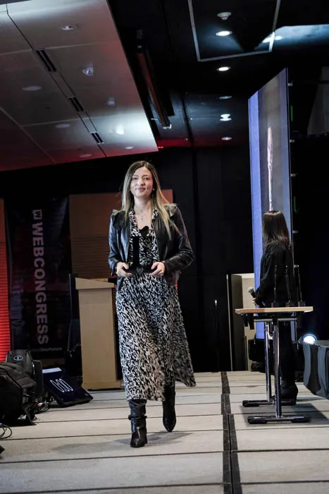 Mujer con abrigo y falda estampada camina por el escenario durante la premiación Mujeres Épicas 2022