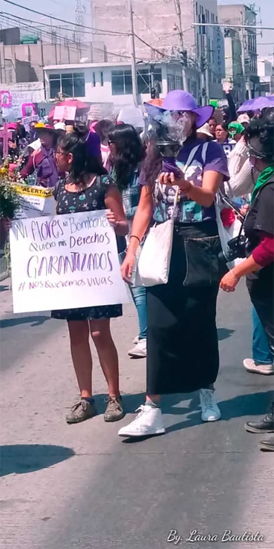 Mujer con una pancarta avanza entre manifestantes vestidas de morado en la marcha del 8M en Nezahualcóyotl