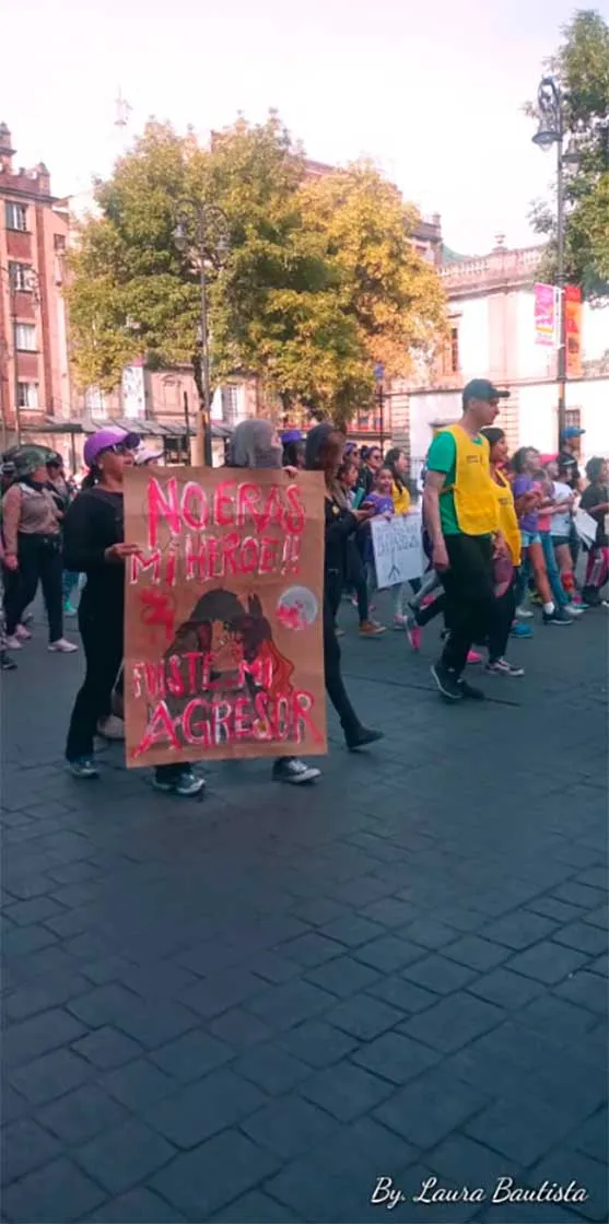 Mujer de espaldas con pancarta marchando por una plaza en la marcha del 8M en Nezahualcóyotl