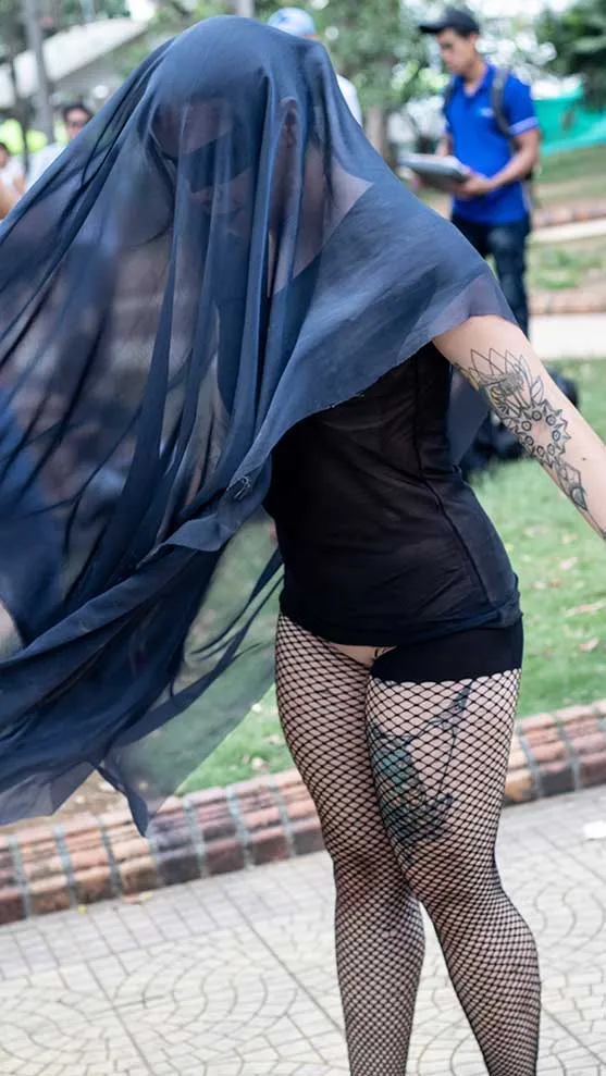 Mujer con una tela oscura sobre la cabeza y medias de red en un parque durante el 8M en Bucaramanga