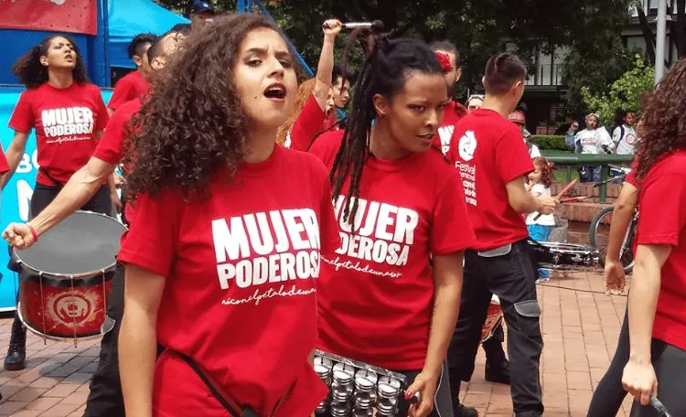Mujeres con camisetas rojas «Mujer poderosa» tocan tambores y cantan en la ciclovía