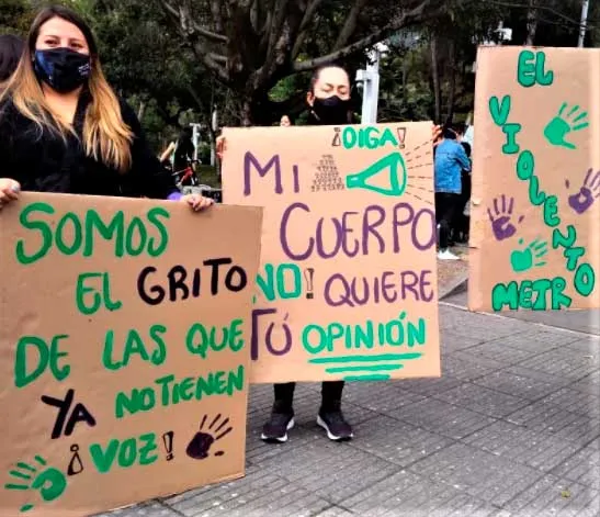 Mujeres con carteles de cartón verde que dicen «Somos el grito de las que ya no tienen voz» y «Mi cuerpo no quiere tu opinión»