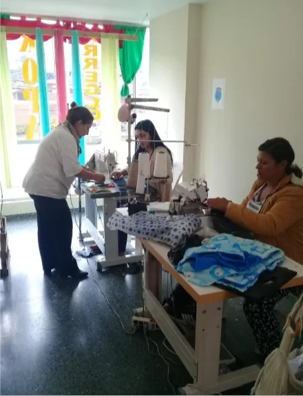 Mujeres cosen en máquinas dentro de un taller luminoso de costura, con una mujer de pie que las guía