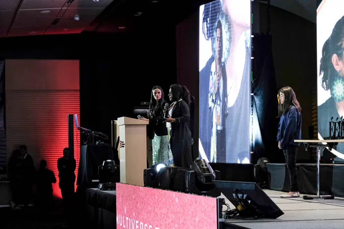 Tres mujeres en el escenario junto a un atril, con pantallas grandes detrás, en la premiación Mujeres Épicas 2022
