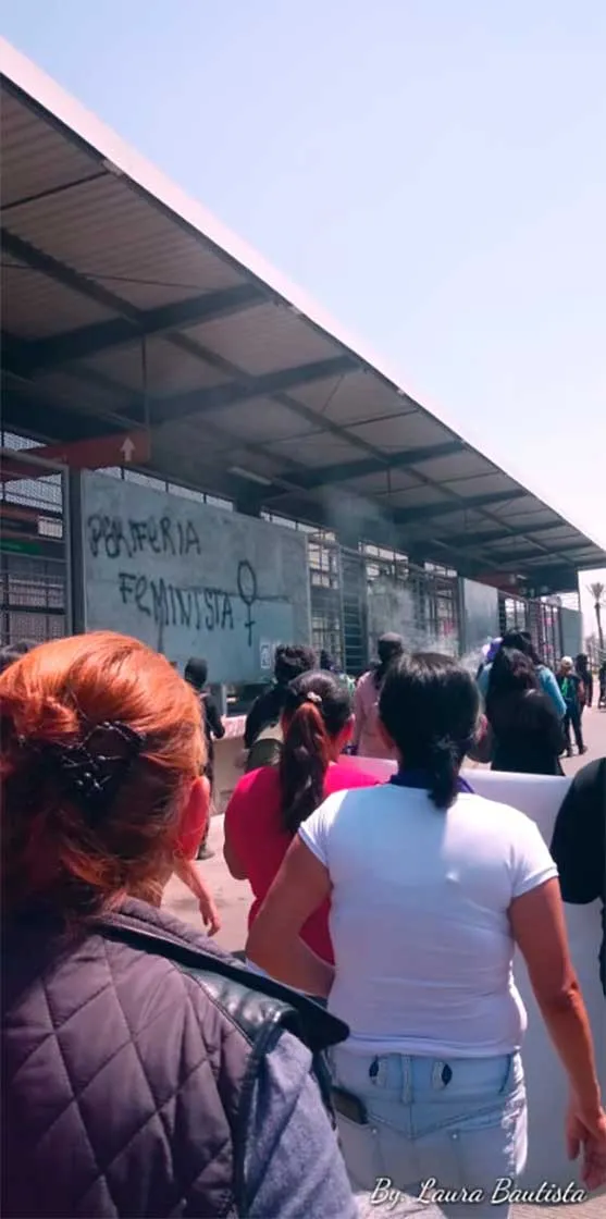Mujeres de espaldas caminando junto a una estación de transporte en la marcha del 8M