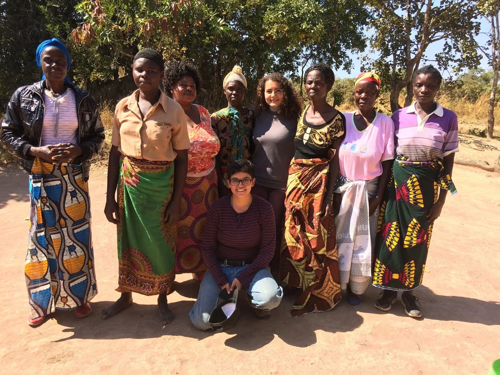 Grupo de mujeres con telas estampadas de colores posa en un camino de tierra en Kasama, Zambia
