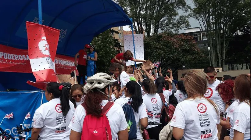 Multitud con camisetas blancas «Mujer poderosa» frente a una tarima con carpa azul y banderines