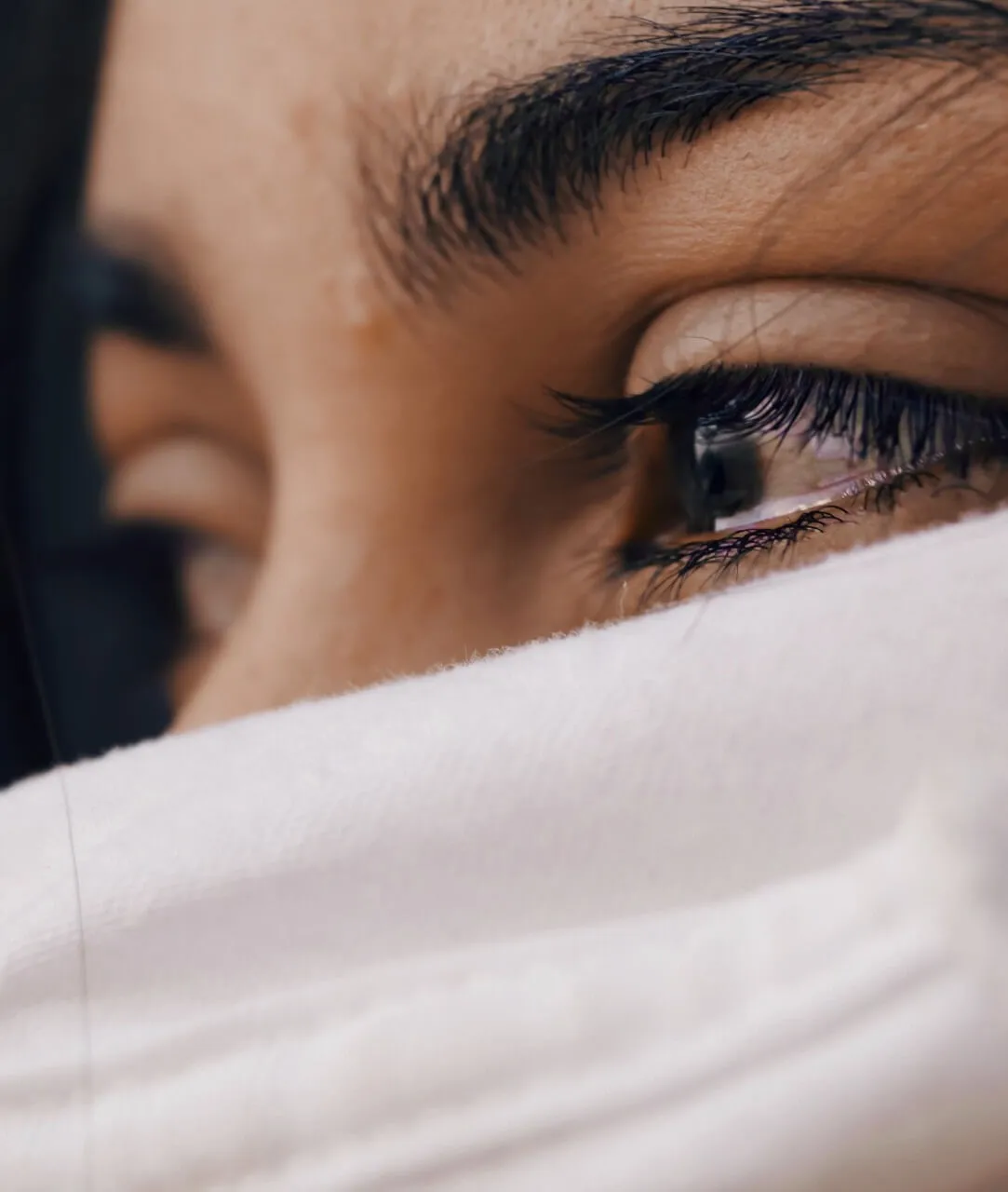 Primer plano de los ojos de una mujer con el rostro parcialmente cubierto por una tela blanca