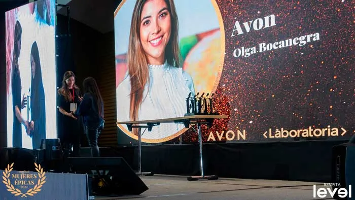 Pantalla con el retrato de Olga Bocanegra y el logo de Avon en la gala Mujeres Épicas de Revista Level