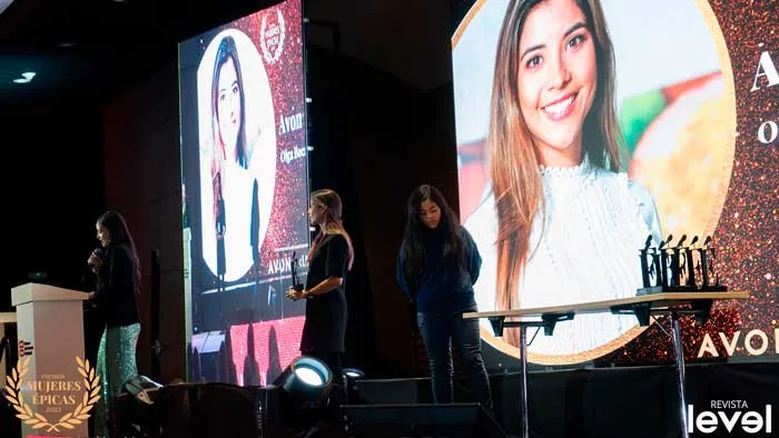 Mujeres junto a la mesa de premios frente a una pantalla con el retrato de Olga Bocanegra, en Mujeres Épicas de Revista Level