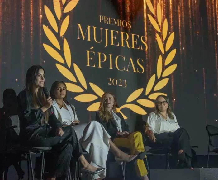 Cuatro mujeres sentadas en un panel bajo el logo dorado de laurel de los Premios Mujeres Épicas 2023