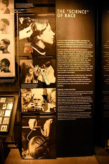 Panel de museo con textos y fotografías sobre «La ciencia de la raza», en una sala oscura