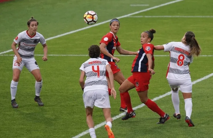 Partido de fútbol femenino con jugadoras de camiseta blanca y roja disputando el balón