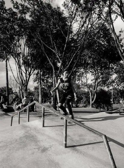 Patinadora se desliza sobre una barandilla metálica en un skatepark, en blanco y negro