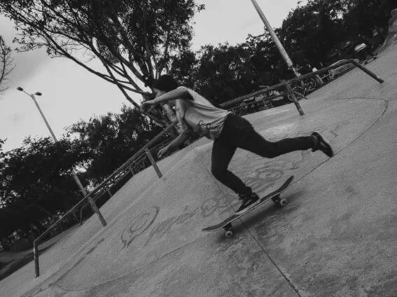 Patinadora sobre su tabla desciende por la rampa de un skatepark, en blanco y negro