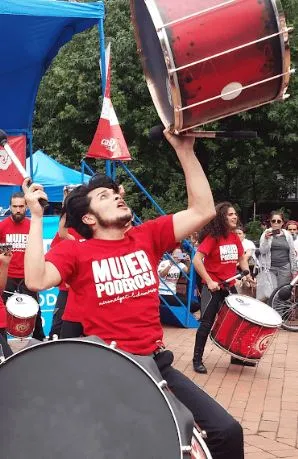 Percusionista con camiseta roja alza un bombo grande durante una presentación en la ciclovía