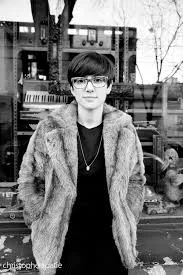Retrato en blanco y negro de una persona con gafas y abrigo de piel en una calle