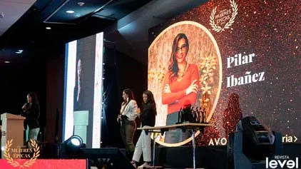 Pantalla con Pilar Ibañez y mujeres de pie junto a la mesa de premios en la gala Mujeres Épicas de Revista Level