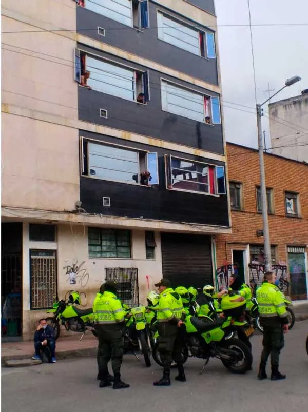Policías con chalecos verdes fluorescentes y motocicletas frente a un edificio en una calle de Bogotá