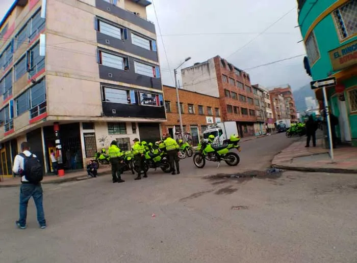 Policías con chalecos verdes fluorescentes y motocicletas en una esquina frente a edificios de ladrillo