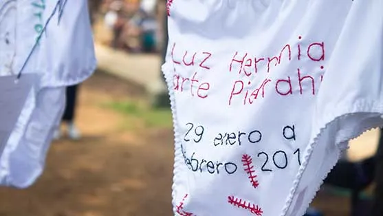 Prenda interior blanca bordada con un nombre de mujer y fechas, colgada como acción de memoria en el 8M en Bucaramanga
