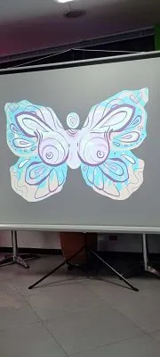 Proyección de una mariposa azul y blanca dibujada sobre una pantalla en una sala de la exposición Aletea