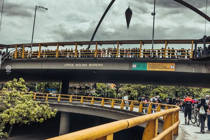 Puente amarillo con personas asomadas a la baranda bajo un cielo nublado