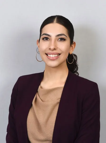 Retrato de Valeria Ávila Guerrero, sonriente, de cabello recogido, aretes de aro y blazer vino