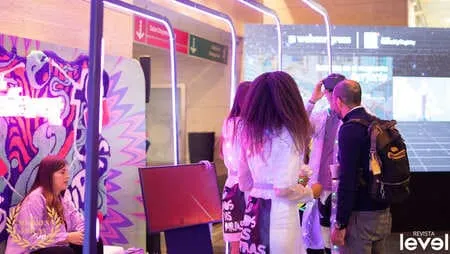 Asistentes conversan junto a un stand con arte colorido en el WebCongress Multiverse, foto de Revista Level