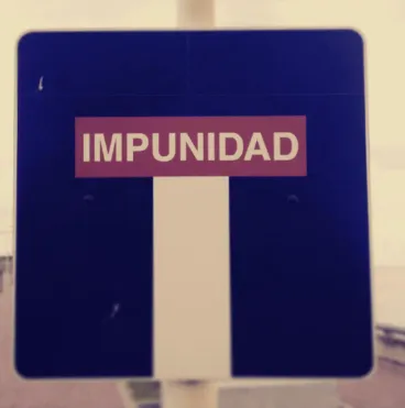 Señal vial azul con la palabra «Impunidad» sobre una calle sin salida
