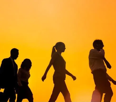 Siluetas de cuatro personas caminando sobre un fondo naranja