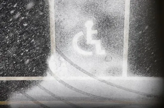 Símbolo de accesibilidad para personas con discapacidad pintado en un estacionamiento cubierto de nieve
