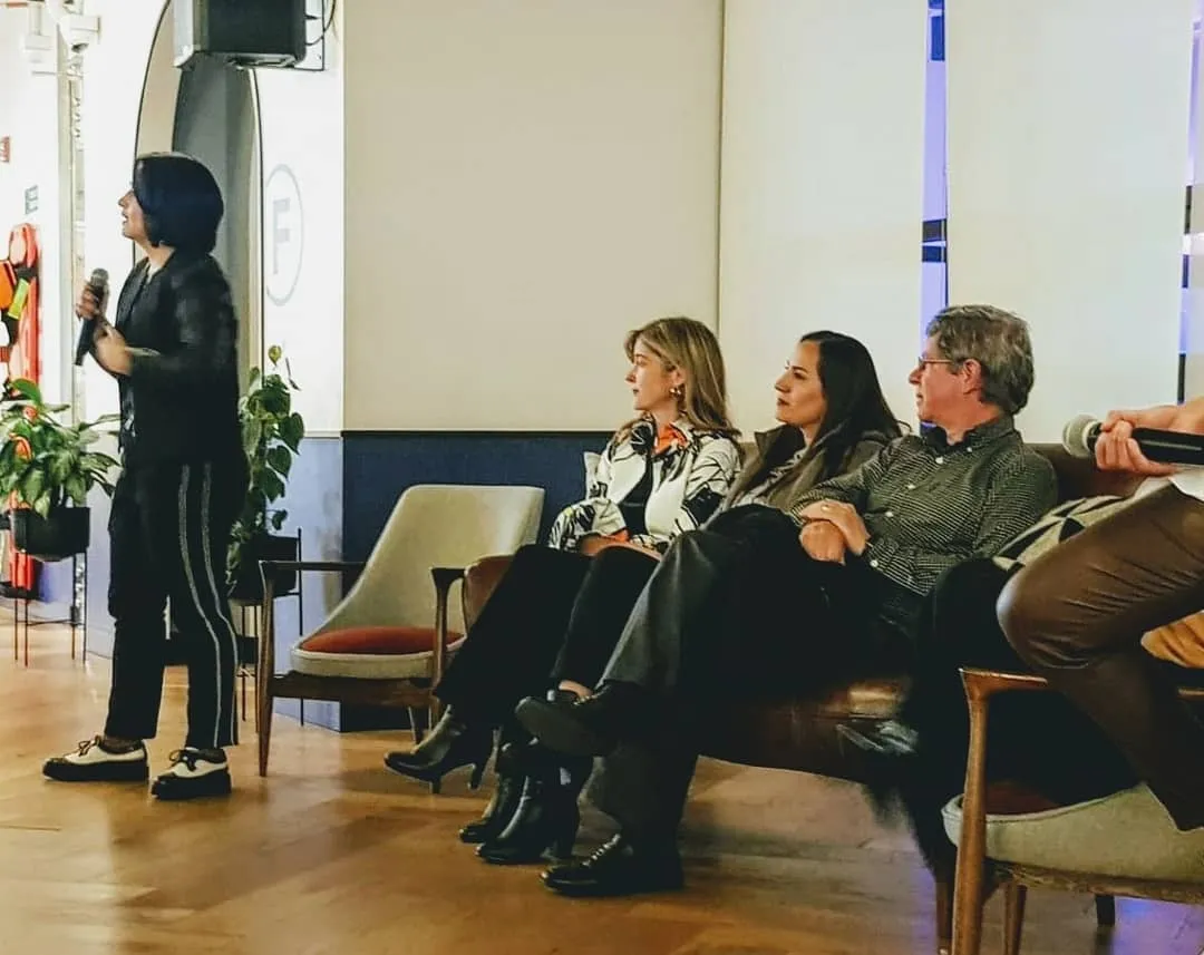 Sindy Hernández, activista feminista, habla de pie con micrófono frente a los panelistas sentados