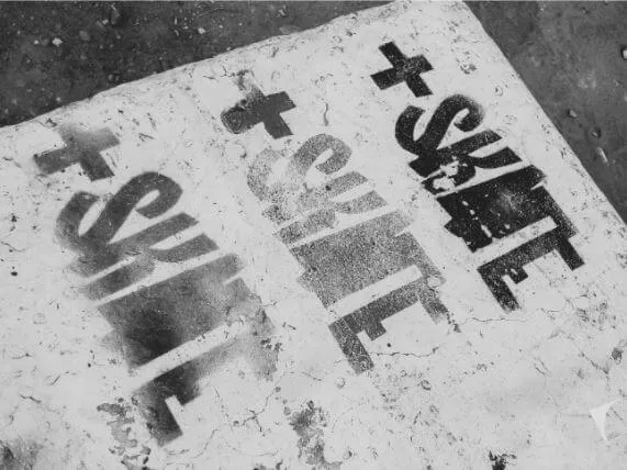 Pintura en el suelo del skatepark con la frase «+Skate» repetida en letras de esténcil