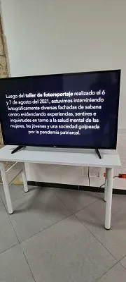 Televisor con un texto sobre el taller de fotoensamblaje en la exposición Aletea