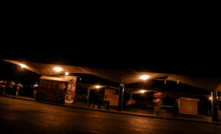 Terminal de transporte de noche con puestos iluminados bajo un techo largo