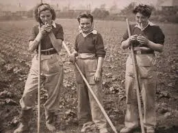Tres mujeres con azadas en un campo de cultivo, en una fotografía antigua en sepia