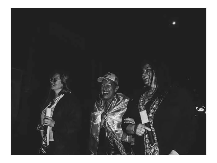 Tres personas envueltas en banderas durante una protesta nocturna, en blanco y negro