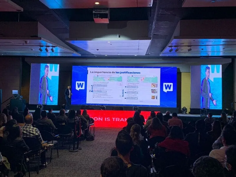 Auditorio lleno del WebCongress Multiverse con una diapositiva sobre la importancia de las publicaciones en pantalla